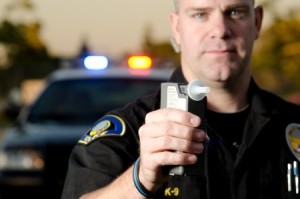 A police officer holds the breath test machine